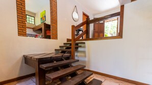 Una escalera de madera con barandilla, un espejo y una ventana con vistas a follaje.