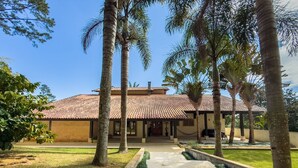 A building with a tiled roof, surrounded by palm trees and a well-maintained lawn.