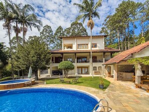 Un edificio de dos pisos con piscina, mobiliario exterior y un patio cubierto.