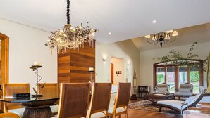 A dining area with a chandelier, wooden chairs, and a table.