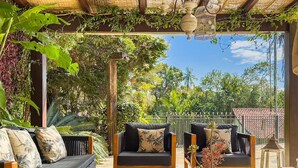 An outdoor seating area with a wooden table, two sofas with cushions, and a potted plant.