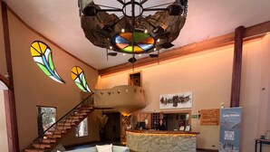 Eine Lobby mit Treppe, Empfangstisch und einem Couchtisch mit Pflanze.