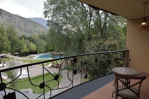 A balcony with a view of a river and mountains, outdoor furniture, and a patterned table. - Casa Bosque Lodge (San José de Maipo)