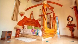 Ein Schlafzimmer mit einem einzigartigen hölzernen Baldachinbett, einem Nachttisch und einem kleinen Radio.