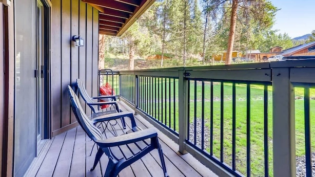 Eine überdachte Terrasse mit Geländer, Tisch und zwei Stühlen.