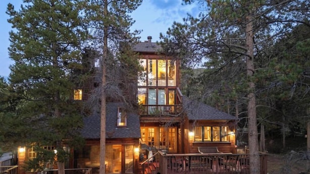 A two-story wooden cabin with a balcony, surrounded by trees. - New Listing! Hot Tub, Sauna, Your Family Mountain Home Getaway! (Keystone)