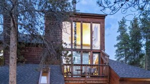 A two-story wooden cabin with a deck, a hot tub, and a large window. - New Listing! Hot Tub, Sauna, Your Family Mountain Home Getaway! (Keystone)
