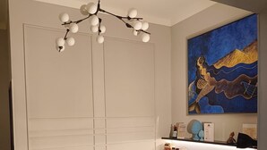 Una sala de estar moderna con un sofá, una mesa de centro, una lámpara colgante y un cuadro abstracto grande en la pared.
