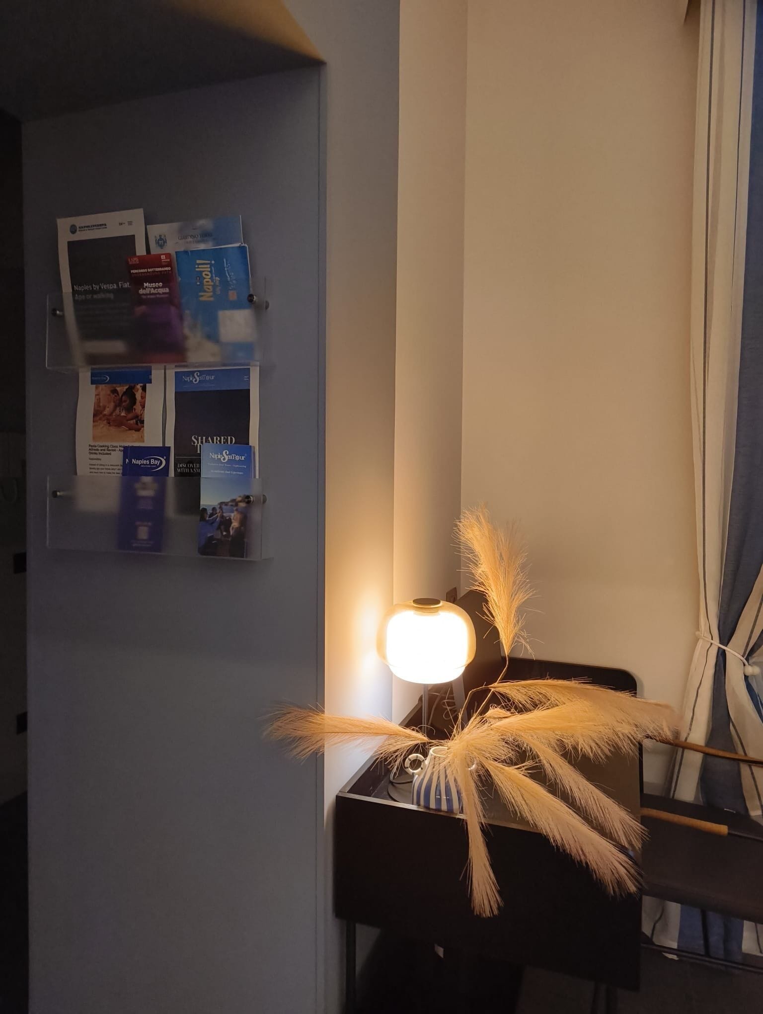 Une pièce comprenant un panneau d’affichage fixé au mur, un bureau avec une lampe et une plante décorative.