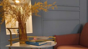 Una habitación con un sofá, una mesita con un jarrón de plantas secas y algunos libros.