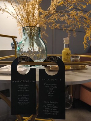 Ein Hotelzimmer mit einer Glasvase, einer Flasche und zwei schwarzen Schildern mit Gästeinformationen.