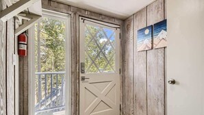 A wooden door with a cross pattern, a fire extinguisher mounted on the wall, and a small outdoor area with a bench. - Amazing Lake and Mountain Views! (Dillon)