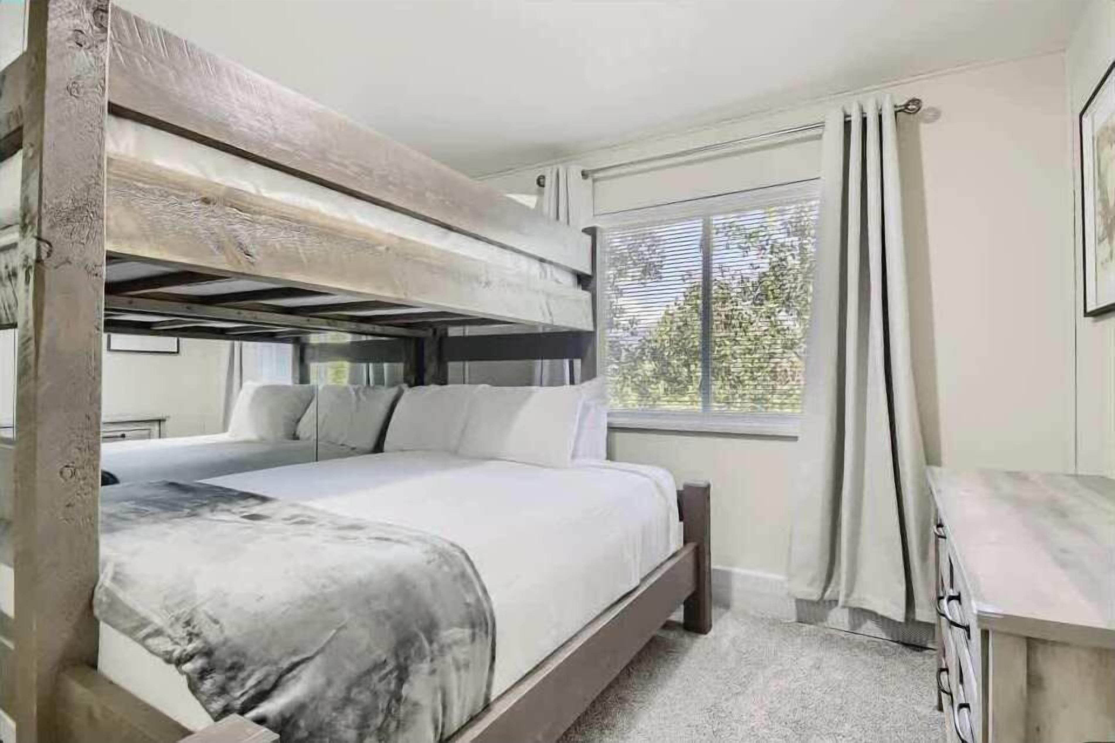 A bunk bed room with a window, a desk, and a chair.