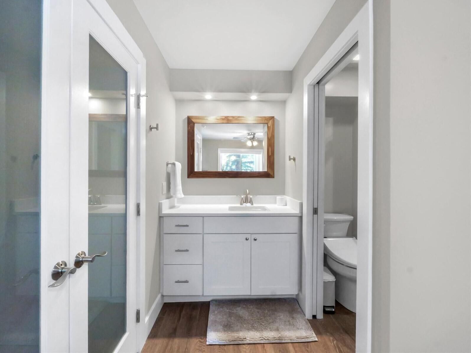 Een moderne badkamer met een wit wastafelmeubel, een spiegel en een toilet.
