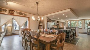 A spacious dining area with a wooden table and chairs, a chandelier, and a view of the kitchen and living area. - Close to Slopes, Pool, & Nature: The Pines Condo in Beautiful Keystone (Keystone)