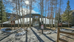 A building with a glass entrance, surrounded by trees and snow, labeled "POOL COMPLEX". - Close to Slopes, Pool, & Nature: The Pines Condo in Beautiful Keystone (Keystone)