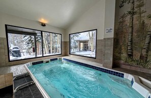A pool with a view of a snowy landscape through large windows. - Close to Slopes, Pool, & Nature: The Pines Condo in Beautiful Keystone (Keystone)