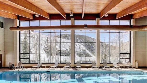 A swimming pool with sunlit windows and lounge chairs. - Close to Slopes, Pool, & Nature: The Pines Condo in Beautiful Keystone (Keystone)