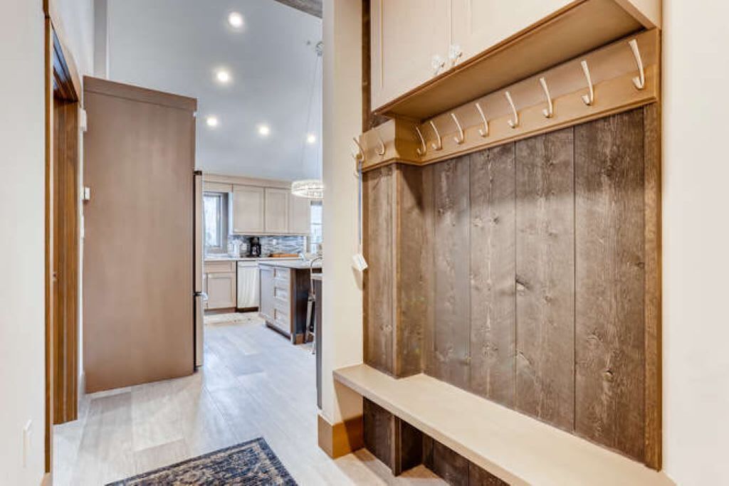 A hallway leading to a kitchen with wooden cabinets and a bench.