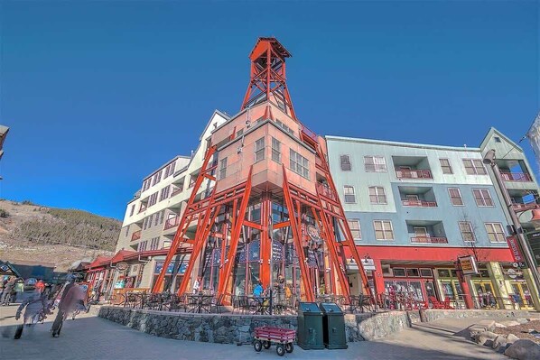 A multi-story building with a prominent red tower structure. - Heart of River Run Village! (Keystone)