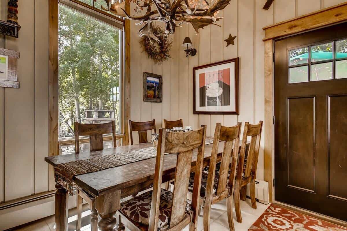 Un coin repas avec une table et des chaises en bois, un lustre et un tableau encadré au mur.