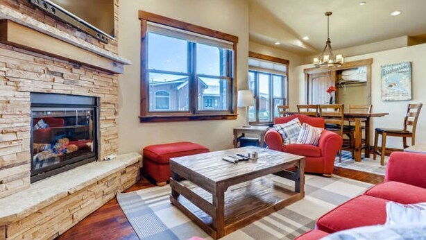 A living room with a fireplace, red furniture, and a dining area with a chandelier. - Amazing Heart of Frisco Condo (Frisco)