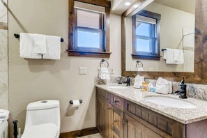 A bathroom with a toilet, two sinks, a mirror, and a window. - Amazing Heart of Frisco Condo (Frisco)