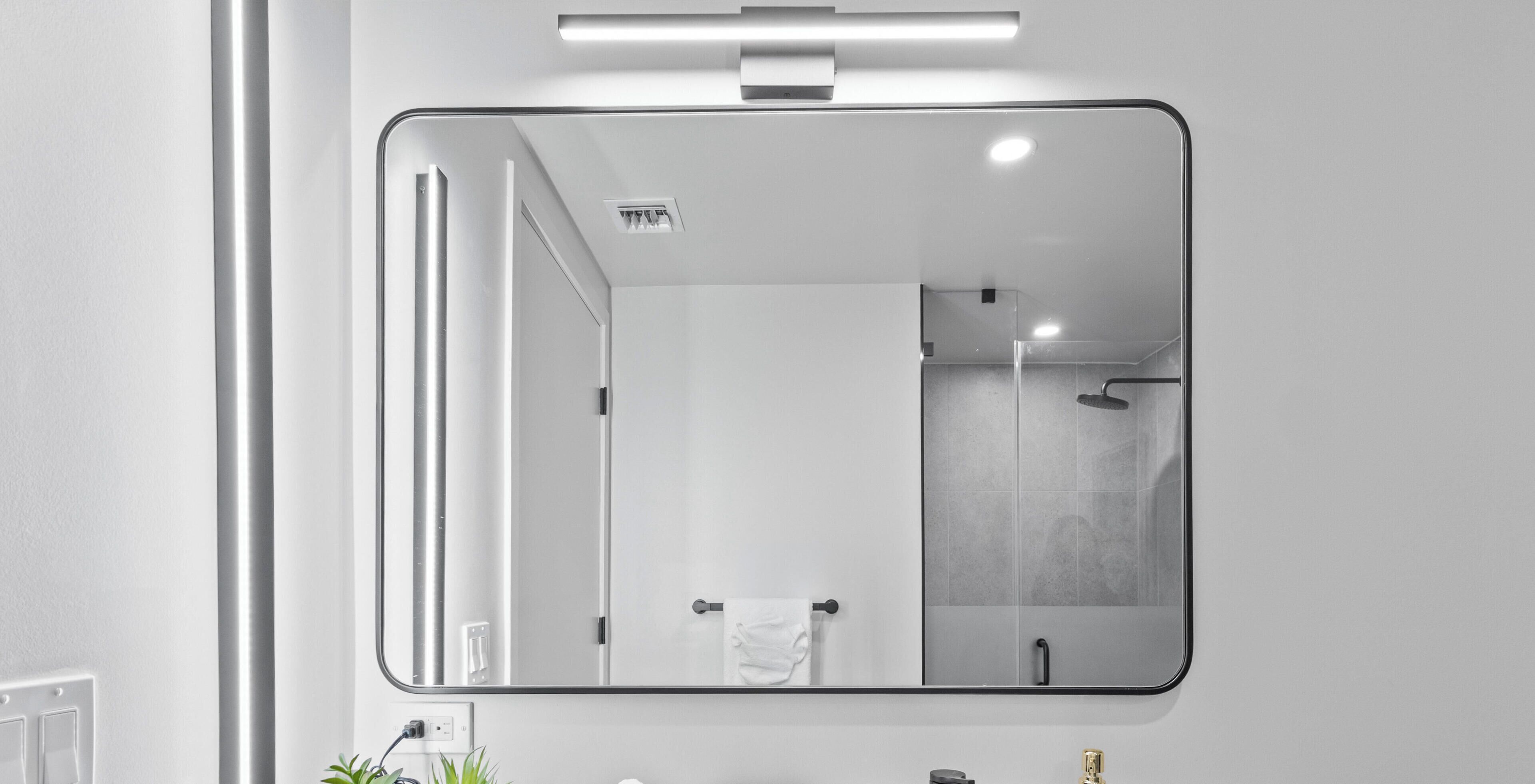 A bathroom with a large mirror, a towel rack, and a shower.