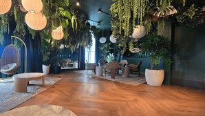 Ein modernes Interieur mit Holzböden, hängenden Pflanzen und einer Sitzecke mit Stühlen und einem runden Tisch.