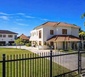 A two-story house with a tiled roof, a front porch, and a black metal fence. - Villa Bella Laguna | Beach Access (Sosúa)