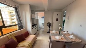 Un espace de vie compact comprenant un canapé, une table à manger et une kitchenette.