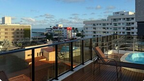 Un balcon avec une piscine, une chaise et une vue sur le paysage urbain.
