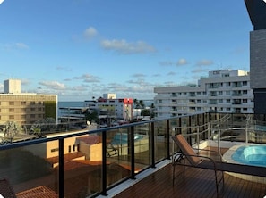 Ein Balkon mit Pool, einem Stuhl und Blick auf die Stadt.