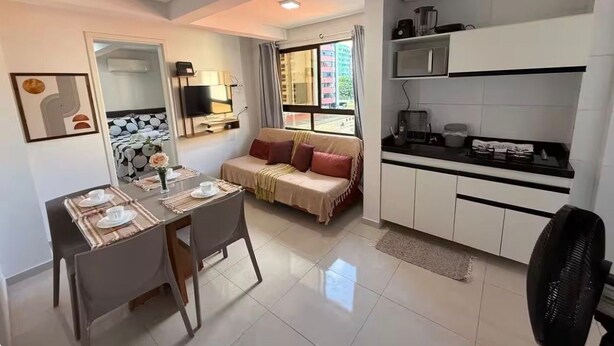 Un espace de vie compact comprenant un coin repas, une kitchenette, un canapé et un téléviseur.