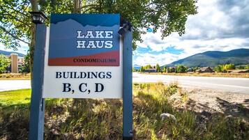 A sign for Lake Haus Condominiums with a view of a road and mountains.
