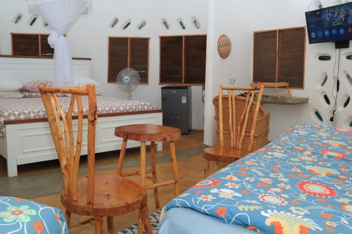 Una habitación con una cama, una silla, una mesita, un ventilador y un televisor.