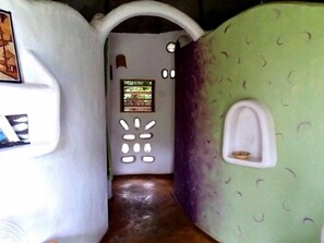 Una habitación con un diseño único, que presenta una pared verde con un patrón de círculos pequeños y una puerta blanca con un ventanal.