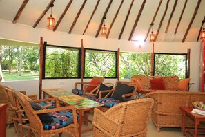 Una habitación con muebles de mimbre, ventanas amplias y faroles colgantes.