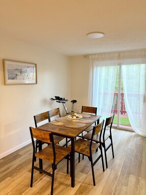 Un comedor con mesa de madera, seis sillas y un cuadro en la pared.