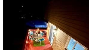 Una terraza con una parrilla, mobiliario exterior y una ventana con persianas.