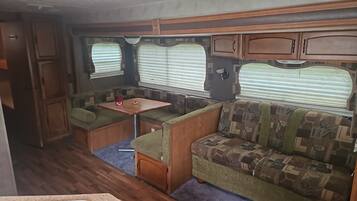 A compact RV interior with a kitchenette, a dining area, and a seating area.