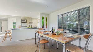 A modern kitchen with a microwave, refrigerator, and wooden island. - Vineyard View - Blenheim Holiday Home (Blenheim)