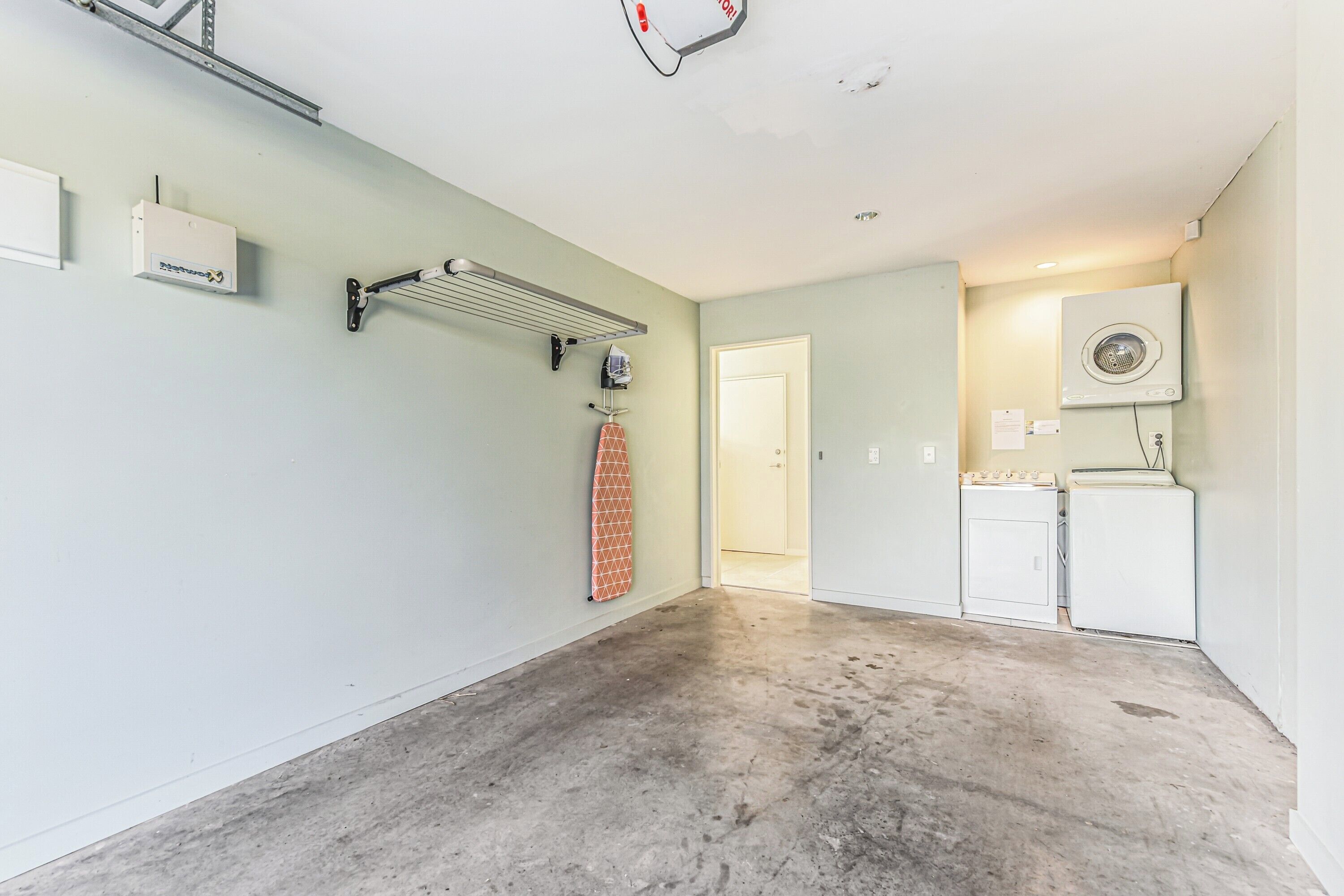 A laundry room with a washing machine, dryer, and a drying rack.
