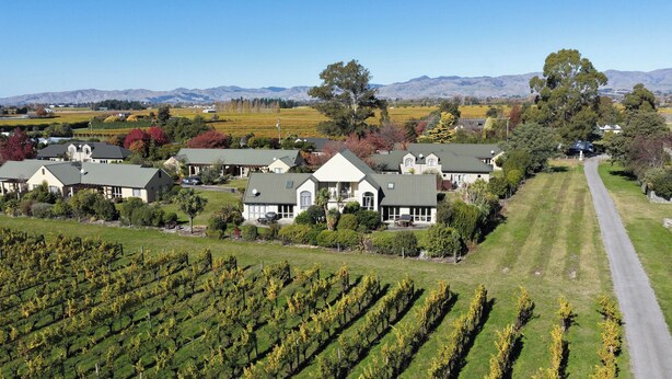 A large estate with multiple buildings, expansive vineyards, and a road leading through the property. - Vineyard View - Blenheim Holiday Home (Blenheim)