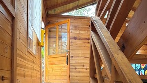 A wooden staircase leading to a door with a glass panel, surrounded by wooden walls and a wooden railing.
