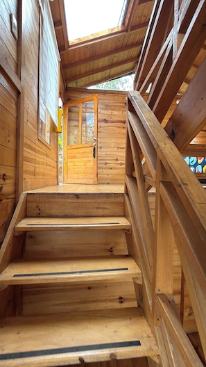 A wooden staircase leading to a door with a glass panel, surrounded by wooden walls and a wooden railing. - Ecocabañas B y B (Choachí)