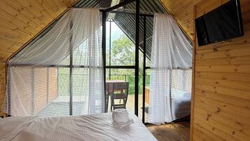 A bedroom with a bed, a TV, and a view of the outdoors.