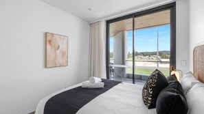 Ein modernes Hotelzimmer mit einem großen Bett, Blick ins Freie und einem Gemälde an der Wand.