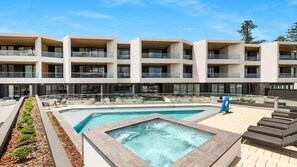 Ein modernes Hotel mit Dachpool, Sitzgelegenheiten im Freien und einem angelegten Garten.