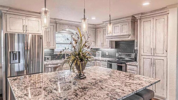 A kitchen with a large granite island, stainless steel appliances, and wooden cabinets. - Vista Moon Main House - Pool, Chapel, Fire Pit (Fredericksburg)